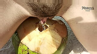 Tiny blonde teen serves pee in a coconut cup outdoors.